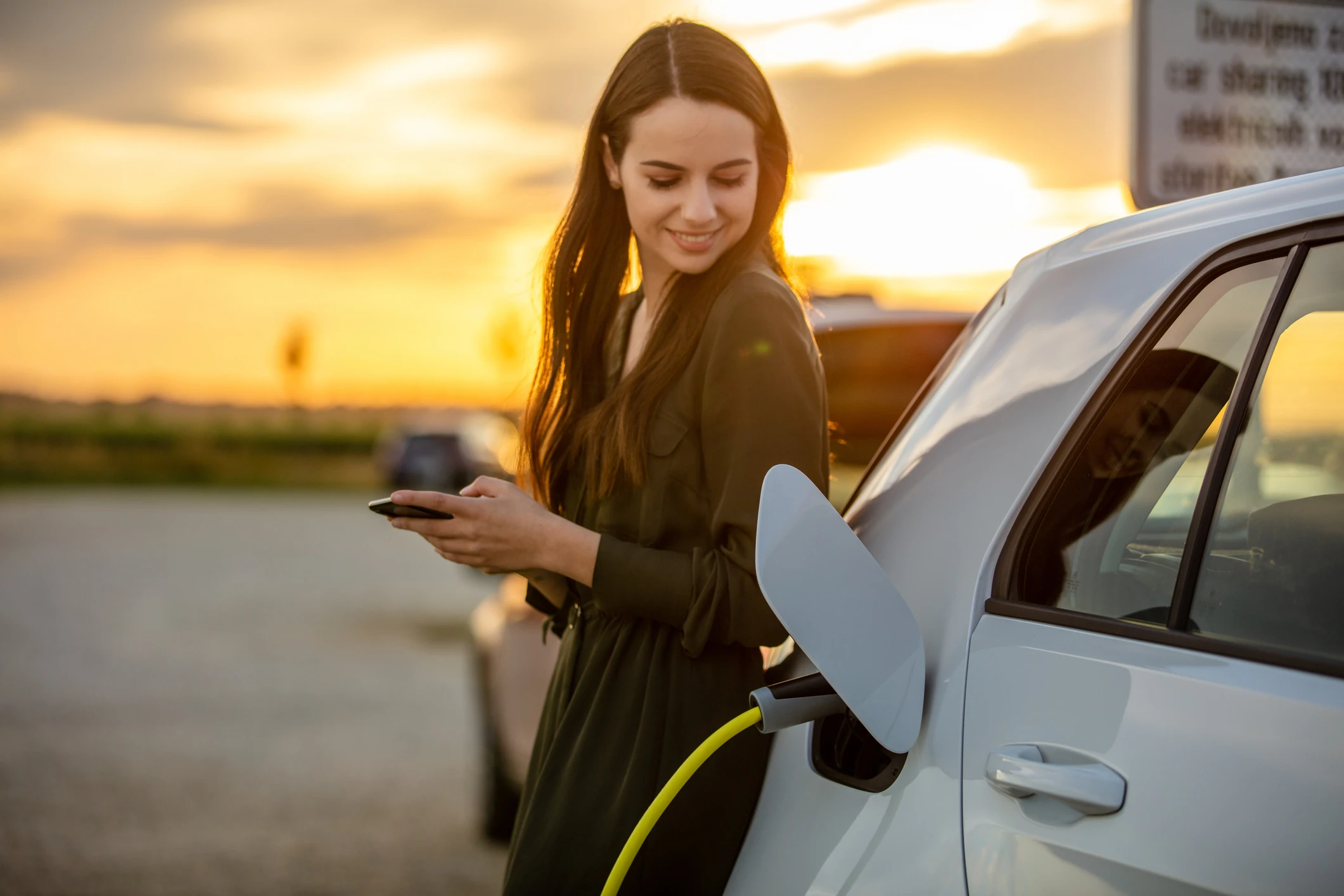 Uśmiechnięta kobieta ładuje używany samochód elektryczny